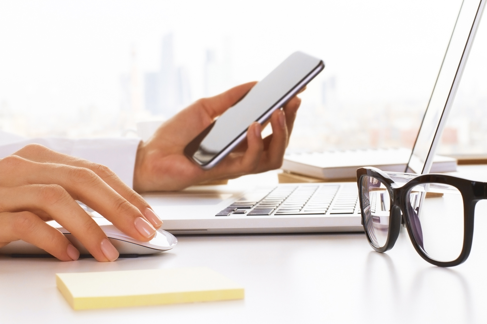Personne travaillant sur ordinateur et téléphone à son bureau